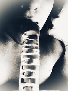 Black and white photo of me sucking on a glass ribbed dildo